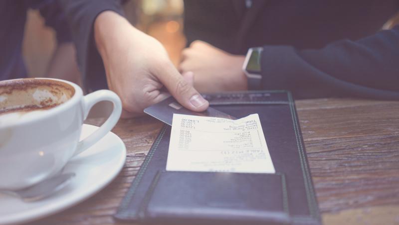 imagine cu mana unui barbat platind nota de plata la un restaurant