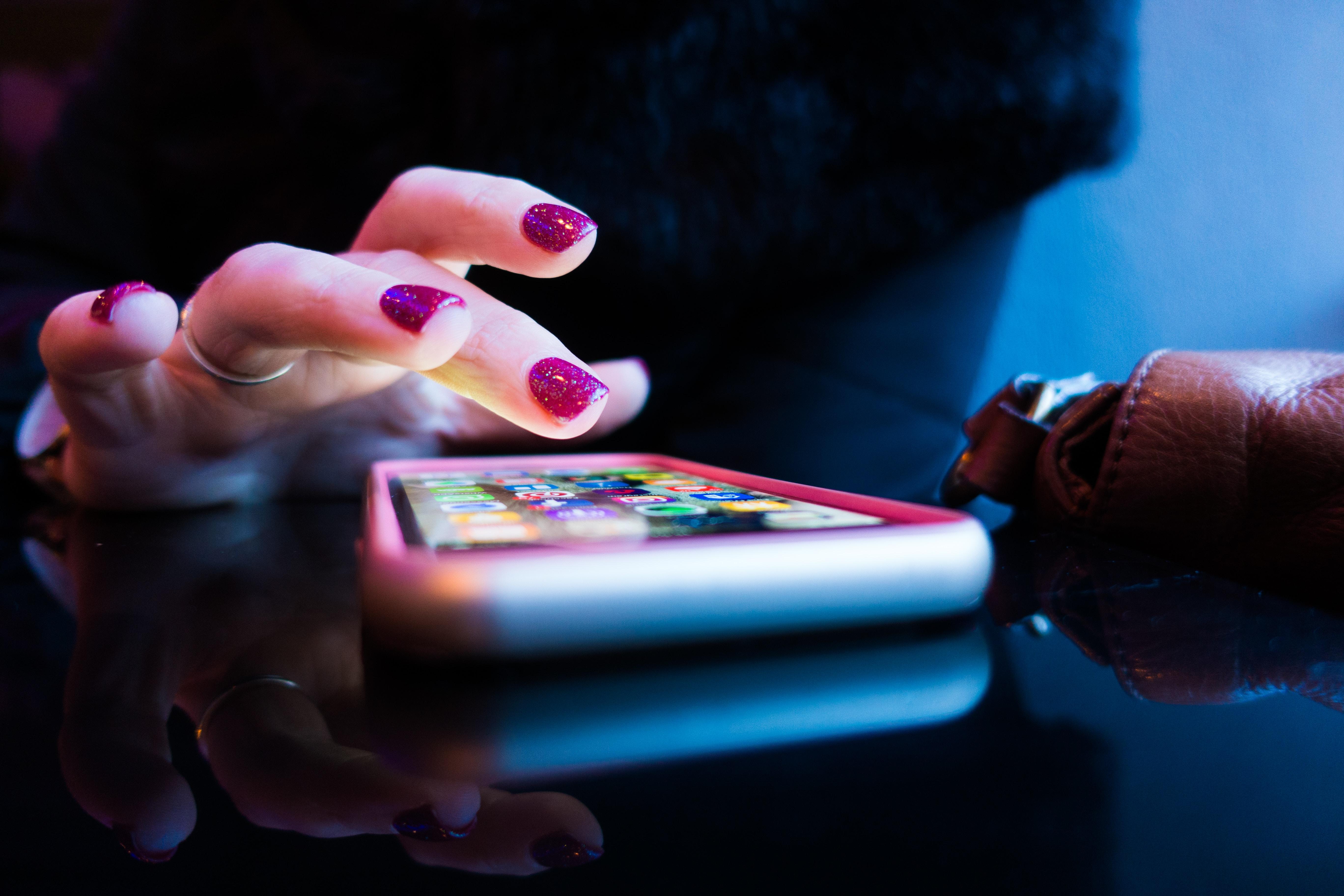 imagine cu mana unei femei care folosește un dispozitiv mobil