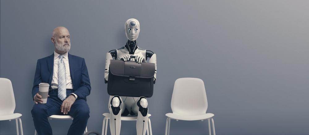 bărbat în costum stă pe scaun lângă un robot cu o servietă