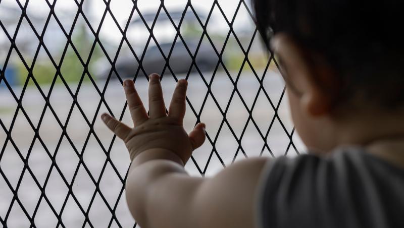 imagine cu un copil care pune mana pe un gard