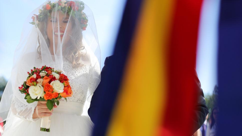 O mireasă fericită și o panglică cu steagul României.