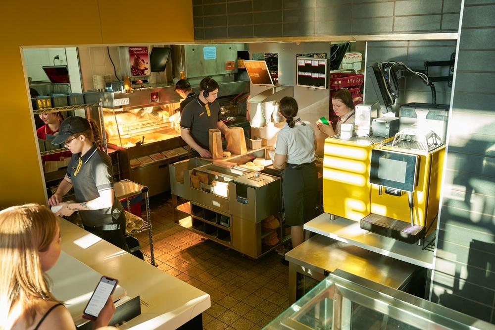 oameni în uniformă de la McDonalds lucrând în bucătăria fast foodului