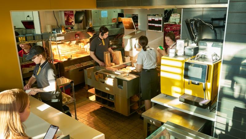 oameni în uniformă de la McDonalds lucrând în bucătăria fast foodului