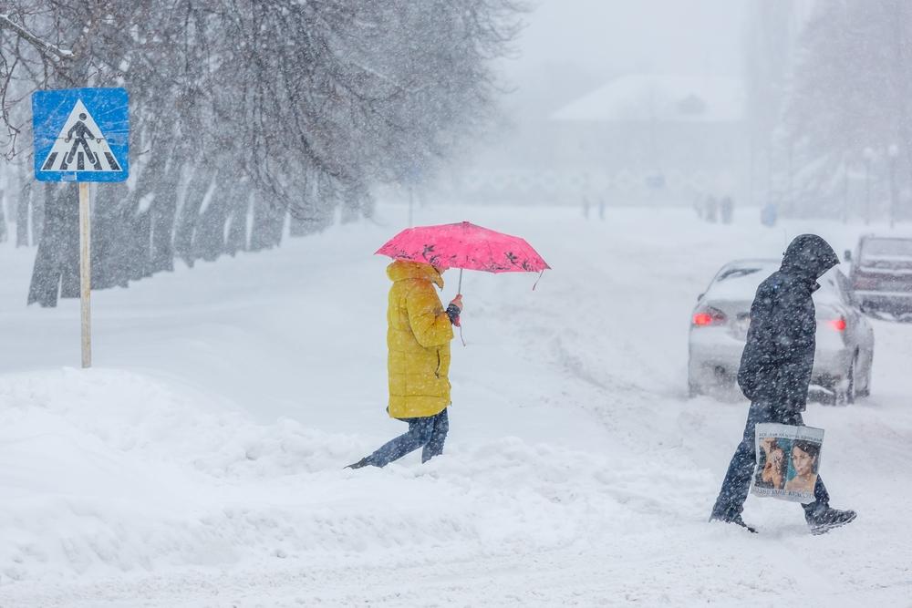 Două persoane mergând prin zăpadă pe stradă