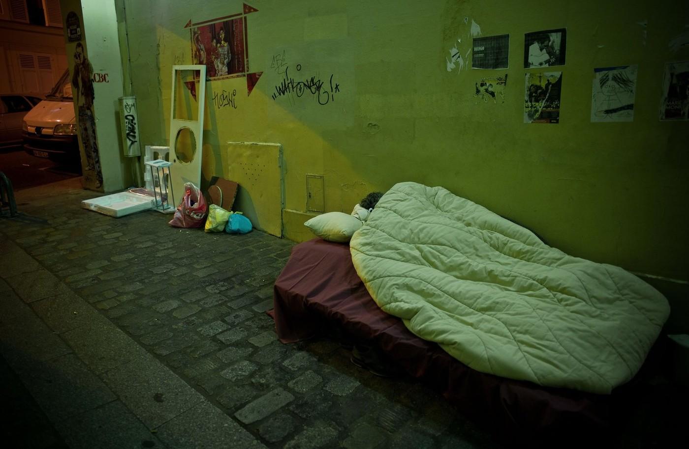 O femeie însărcinată și iubitul ei trăiesc într-un pat pus pe o stradă. Trecătorii trec pe lângă ei și se uită bulversați