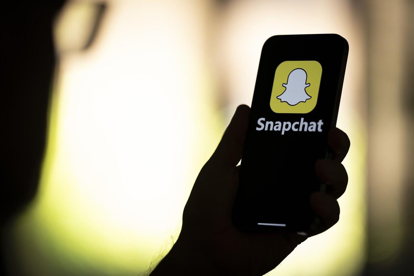 imagine cu o femeie care priveste aplicatia snapchat pe telefonul mobil