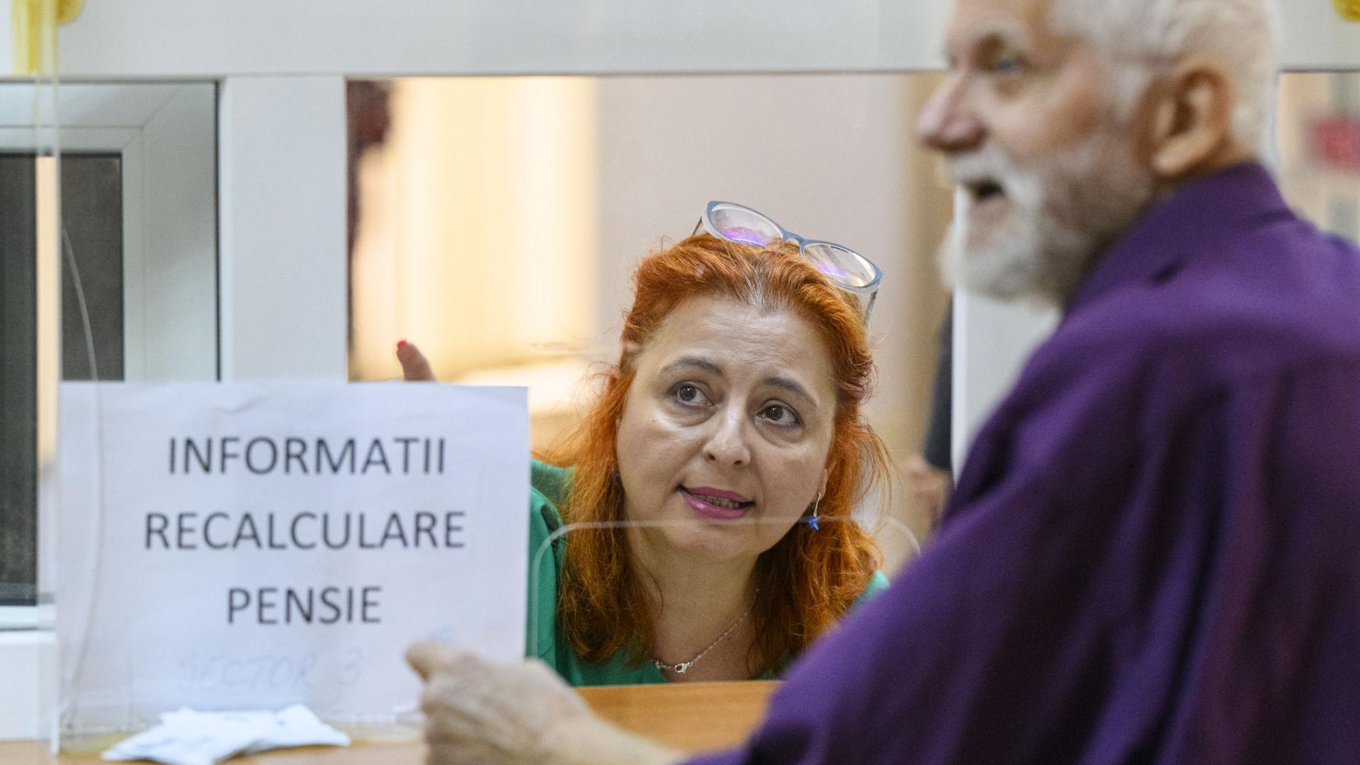 Pensionar care cere informații despre recalcularea pensiei la ghișeu îndrumat de o angajată