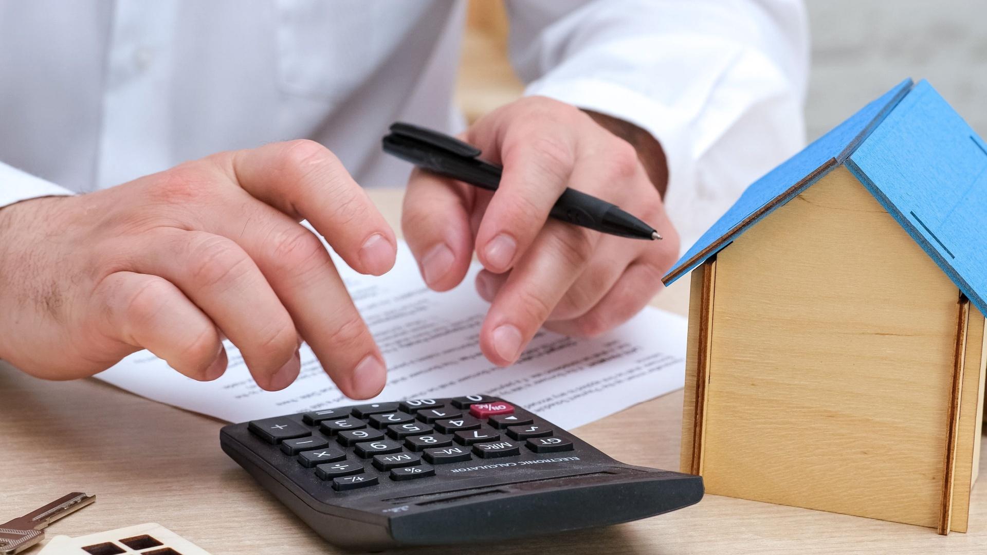 Un bărbat care calculează diferența de costuri lunare dintre proprietățile noi și cele vechi