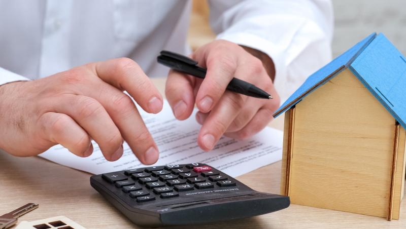Un bărbat care calculează diferența de costuri lunare dintre proprietățile noi și cele vechi