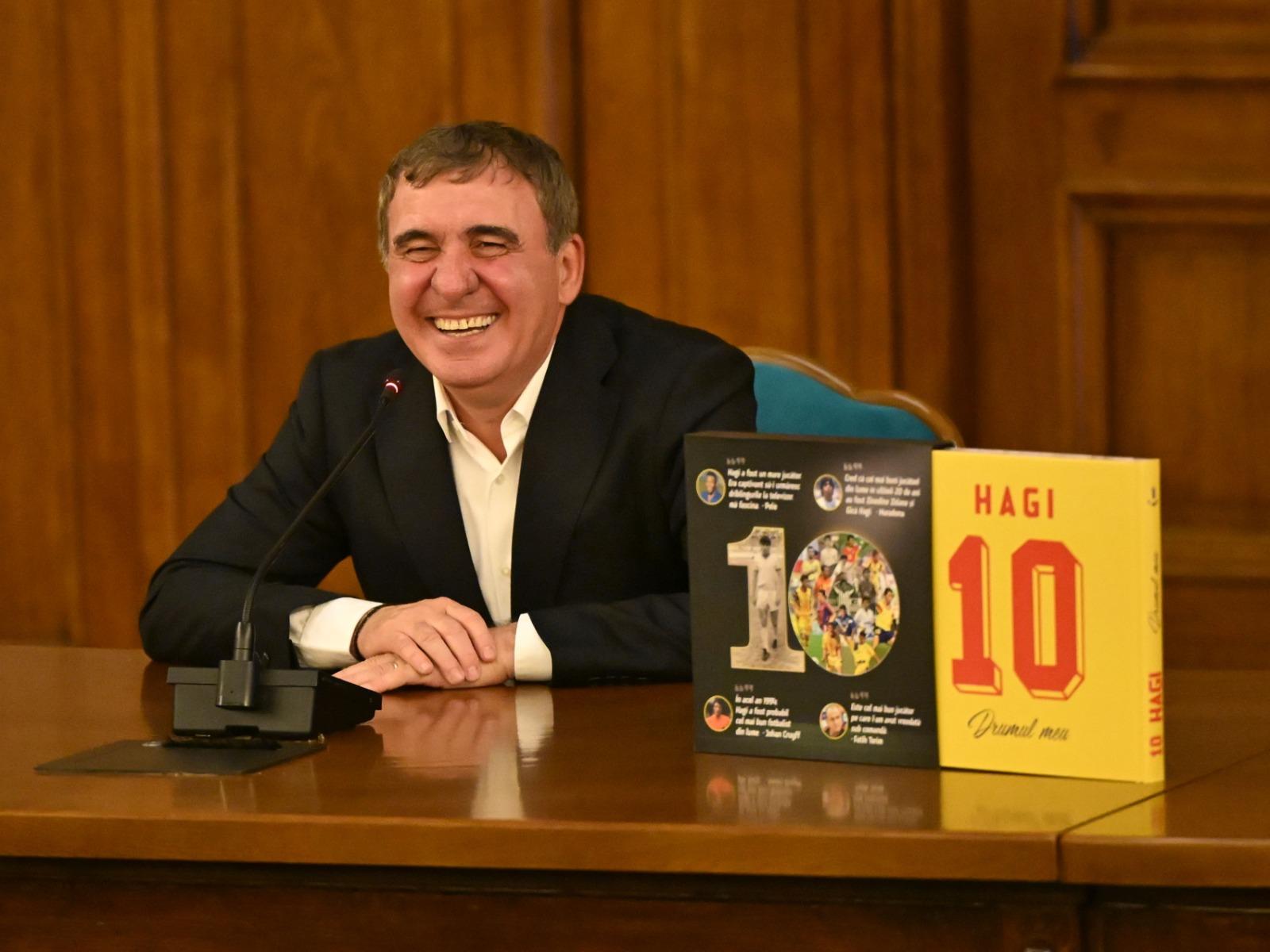 Gheorghe Hagi îmbrăcat cu un costum negru, la o conferință de presă
