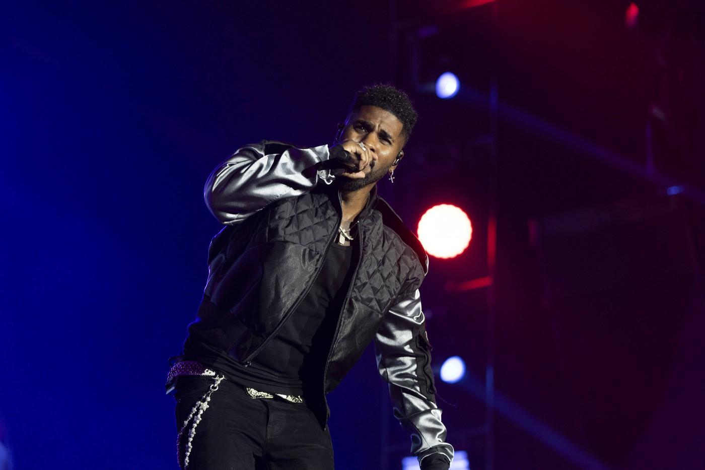 Jason Derulo îmbrăcat într-o ținută neagră, în timp ce cântă la microfon