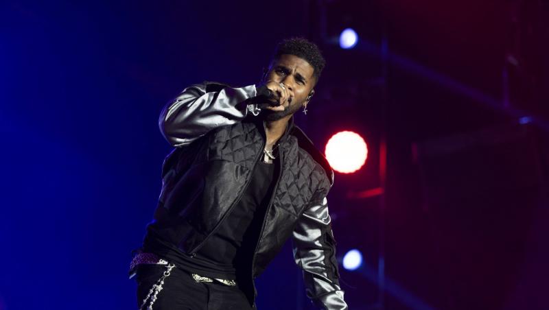 Jason Derulo îmbrăcat într-o ținută neagră, în timp ce cântă la microfon