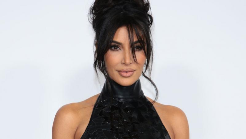 Kim Kardashian îmbrăcată cu un top negru cu mânecile decupate