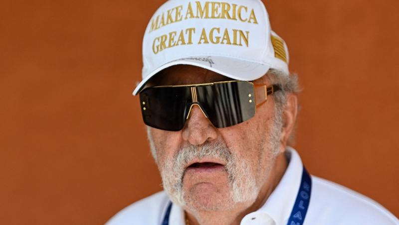 Ion Țiriac îmbrăcat cu o cămașă albă, accesorizată cu o șapcă cu ochelari de soare