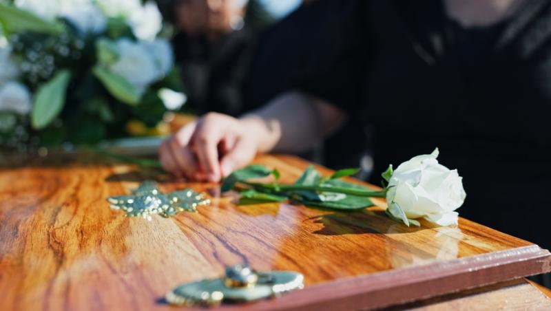 oamen în negru care pun flori pe un coșciug