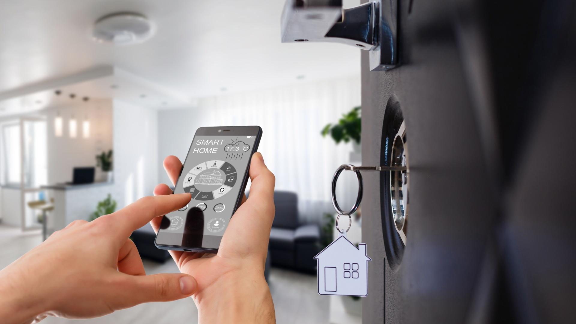 Mâinile unui bărbat care își folosește smartphone-ul pentru automatizarea locuinței