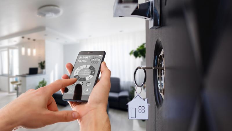 Mâinile unui bărbat care își folosește smartphone-ul pentru automatizarea locuinței