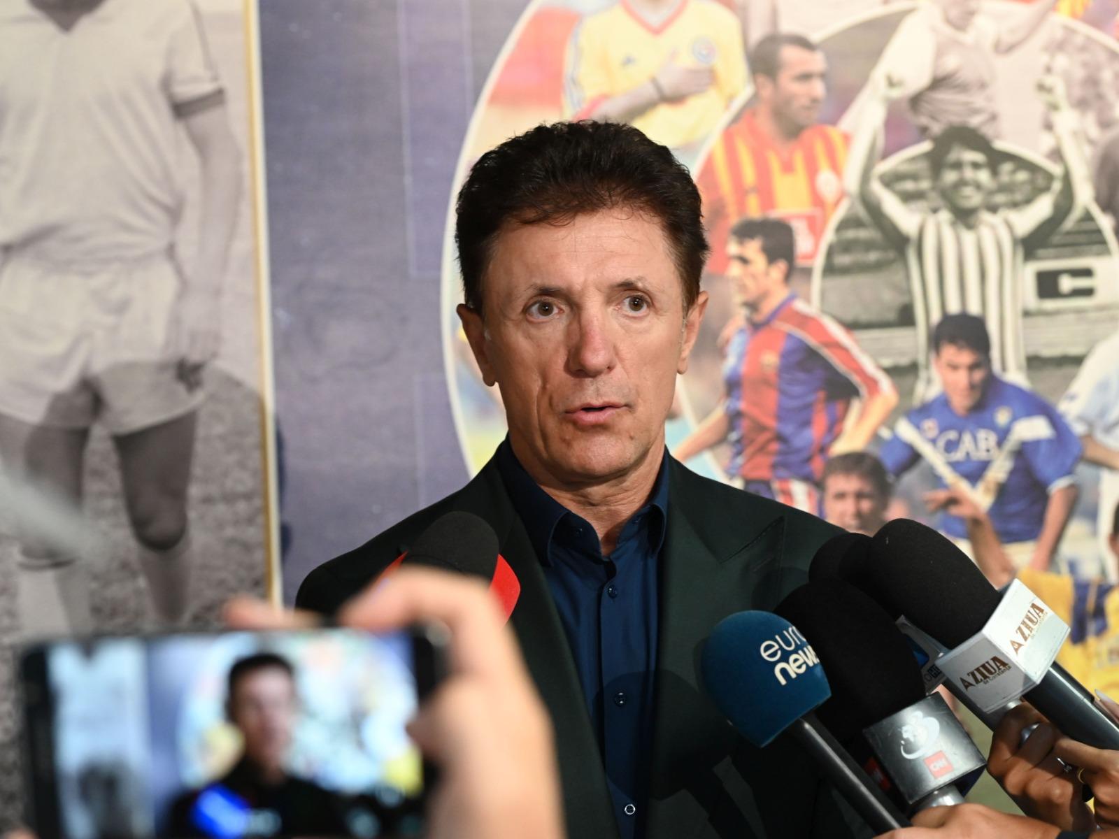 Gică Popescu îmbrăcat cu un costum negru, la o conferință de presă