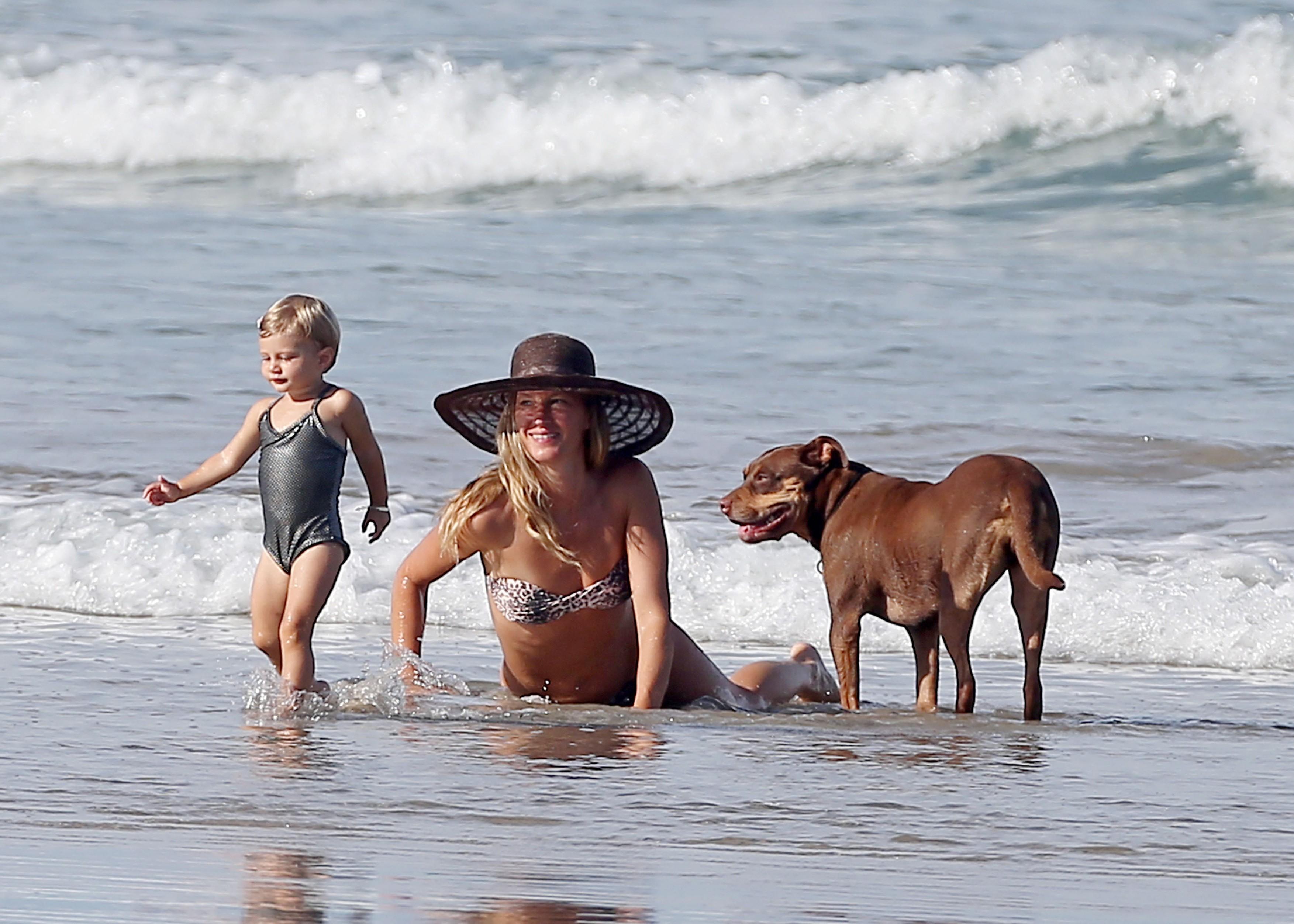 Gisee Bunchen cu copilul și cățelul Lua pe plajă
