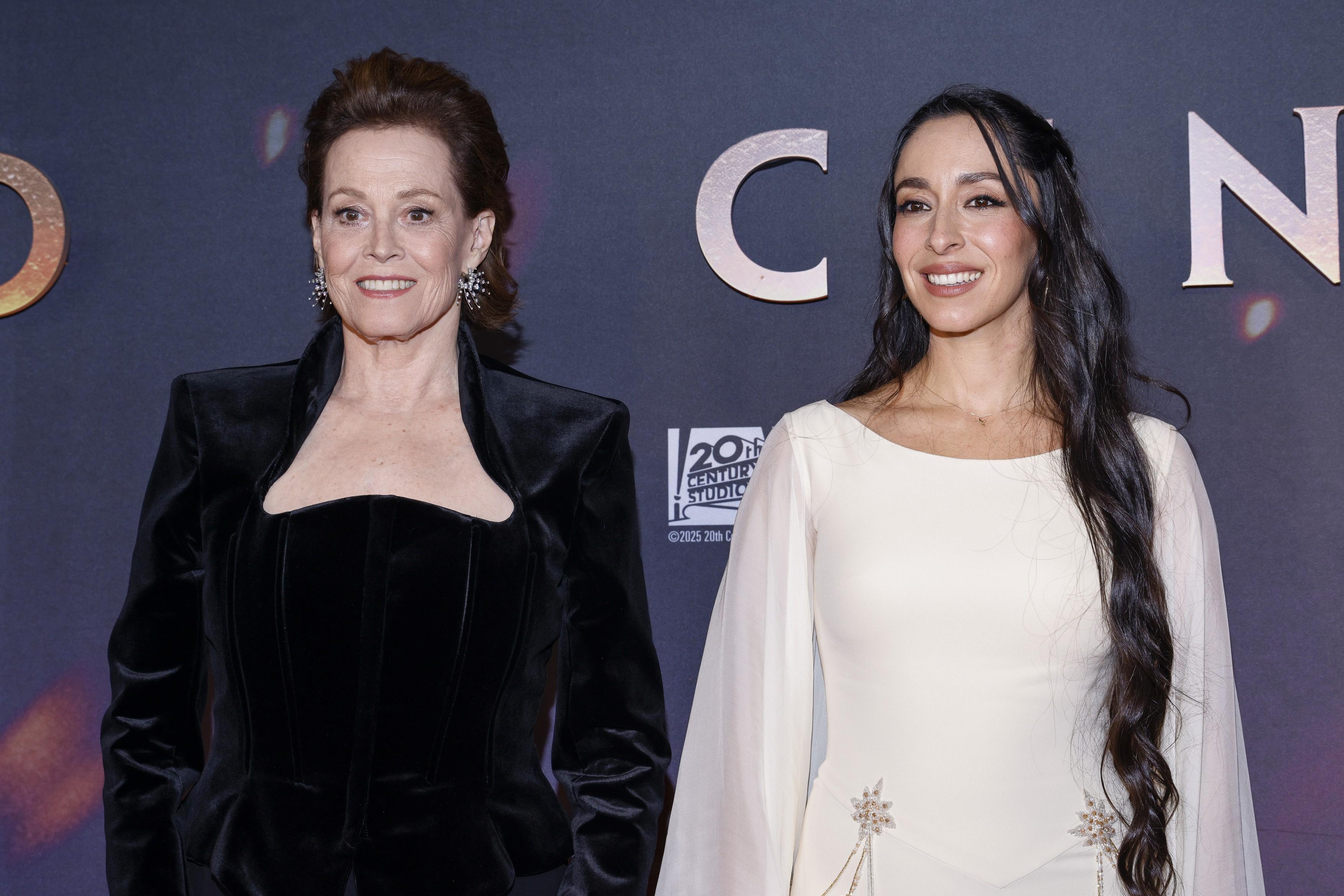 Oona Chaplin, covorul roșu Avatar, decembrie 2025, rochie albă, cu Sigourney Weaver, îmbrăcată în negru