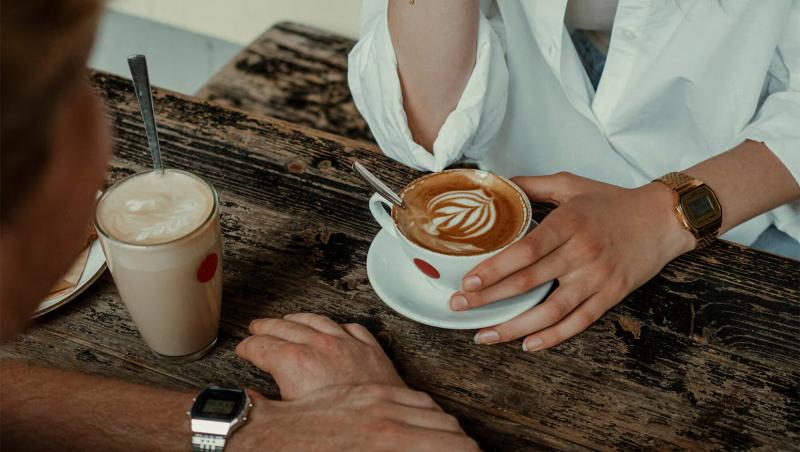 femeie și bărbat la masă cu o cafea în faț și ceasuri casio la mână