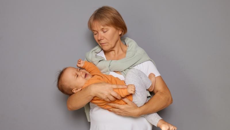 femeie care ține în brațe un copil care plânge