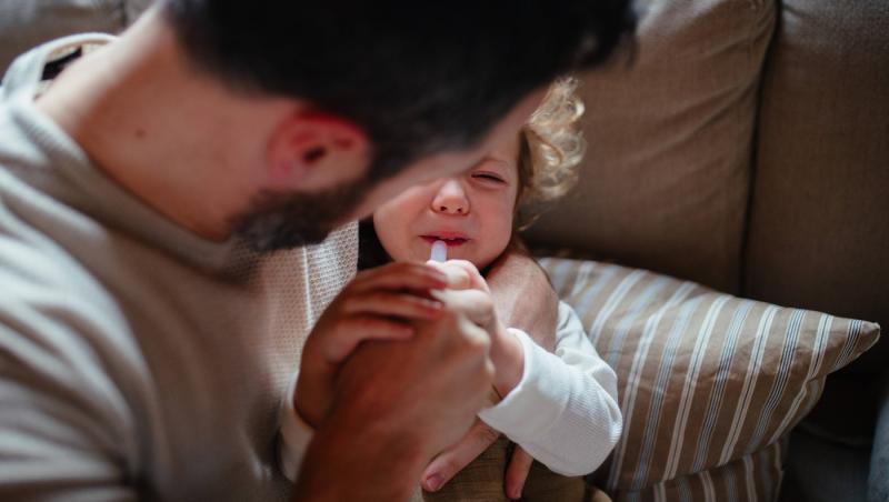 imagine cu un tata care da antibiotice copilului