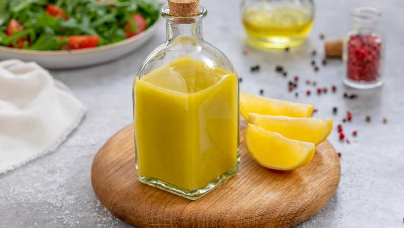 sticlă cu marinadă italienească, jumătate de lămâie și fulgi de chili în fundal