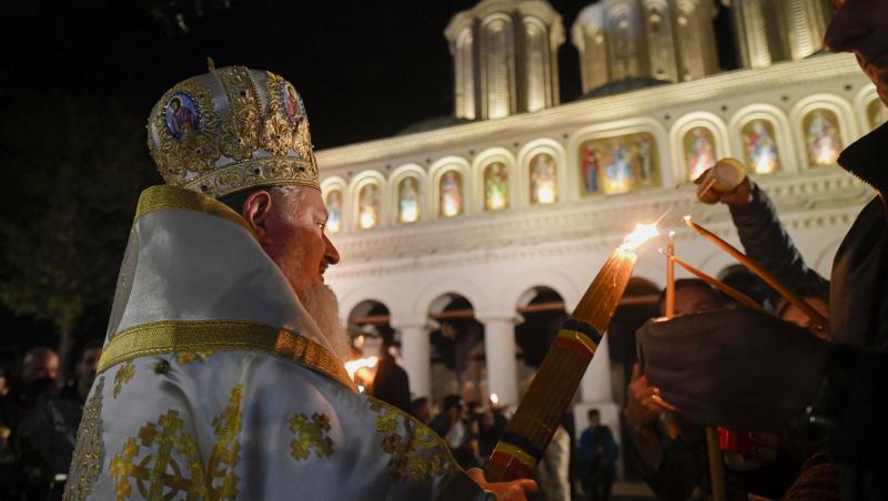 preot care oferă lumina sfântă credincioșilor din curtea bisericii