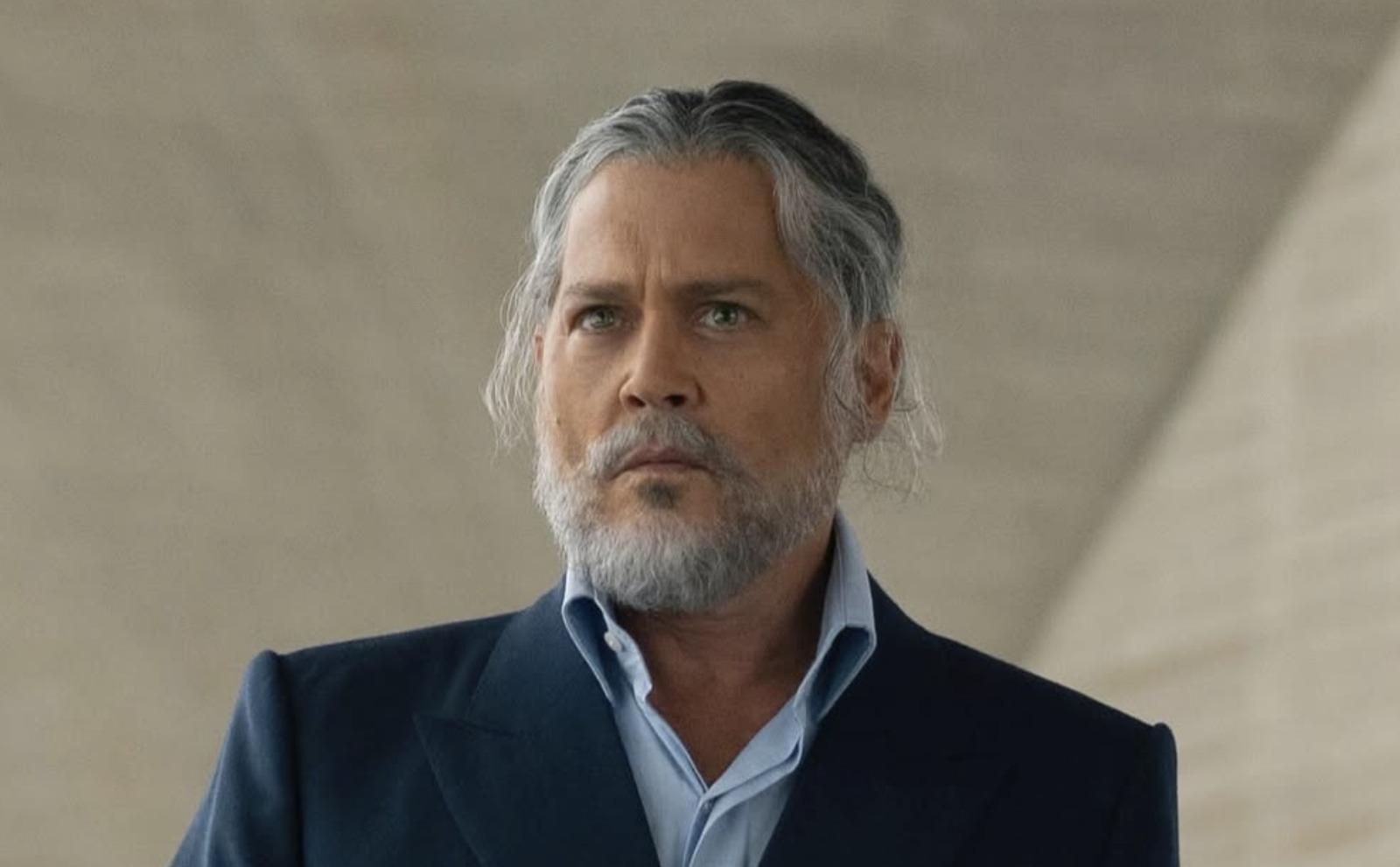 Johnny Depp îmbrăcat cu un costum albastru impecabil, cu barbă lungă și căruntă