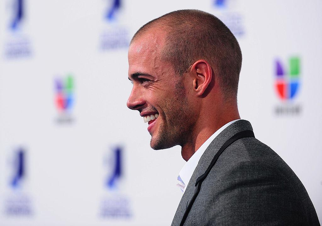 William Levy îmbrăcat cu un costum gri, zâmbind fericit