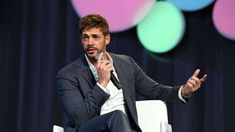 William Levy îmbrăcat cu un costum bleumarin, vorbind la microfon