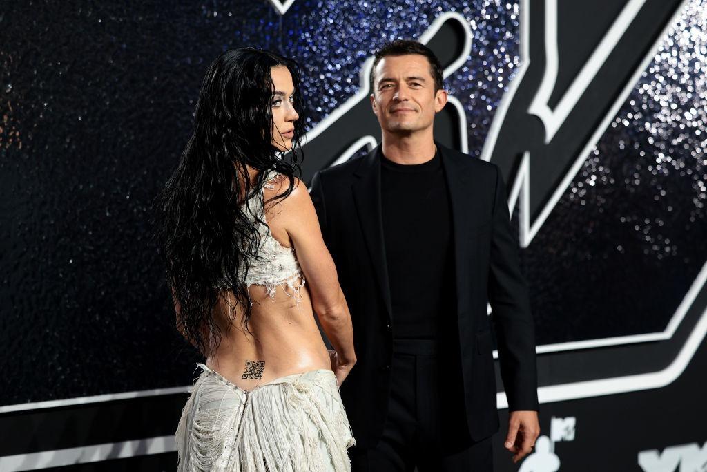 Katy Perry îmbrăcată într-o rochie albă sexy alături de Orlando Bloom îmbrăcat într-o ținută complet neagră