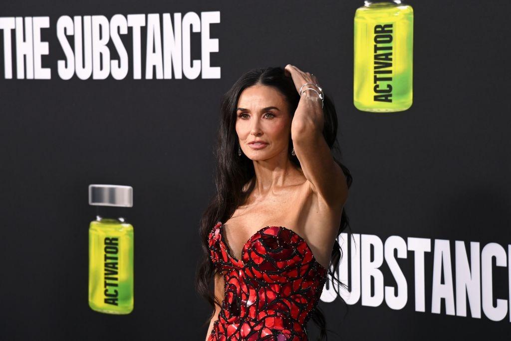 Demi Moore îmbrăcată într-o rochie roșie cu detalii negre, fără mâneci, cu un decolteu sexy