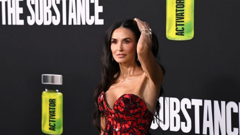 Demi Moore îmbrăcată într-o rochie roșie cu detalii negre, fără mâneci, cu un decolteu sexy