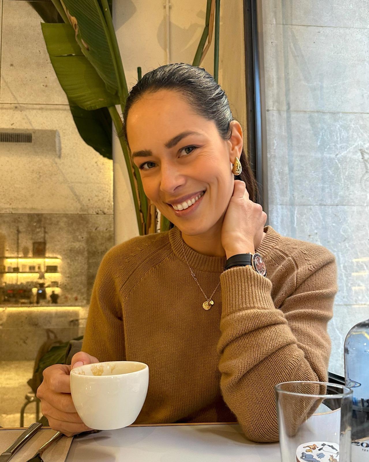 Ana Ivanovic îmbrăcată cu un pulover maro, savurând o cafea