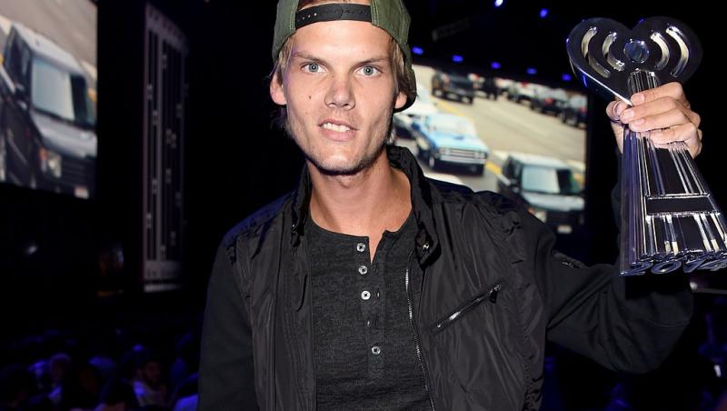 Avicii îmbrăcat în negru, ținând un trofeu în mână