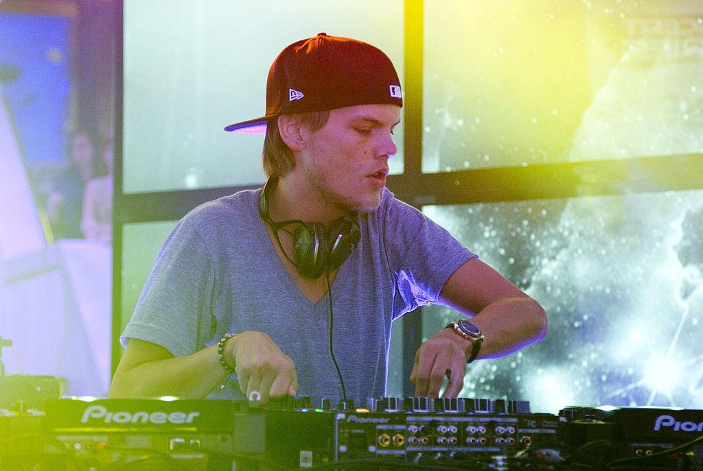 Avicii îmbrăcat cu un tricou gri, mixând muzică pe scenă