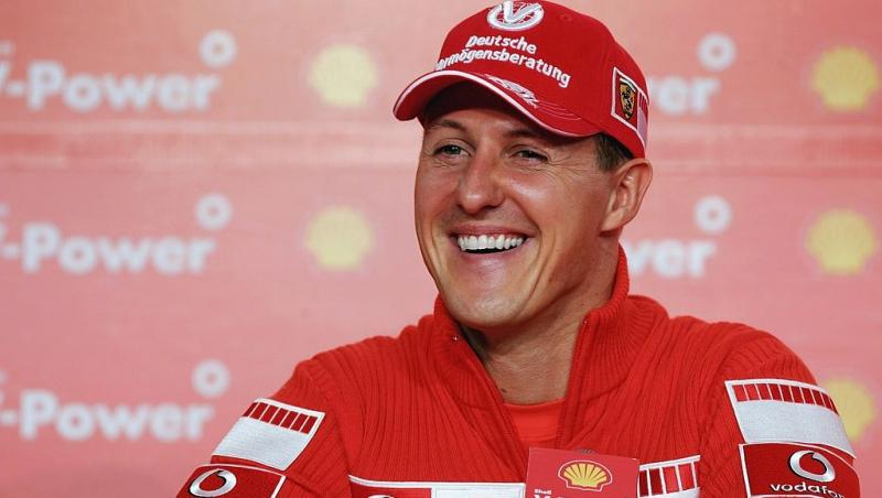 Michael Schumacher îmbrăcat în echipament sportiv roșu, zâmbind la cameră