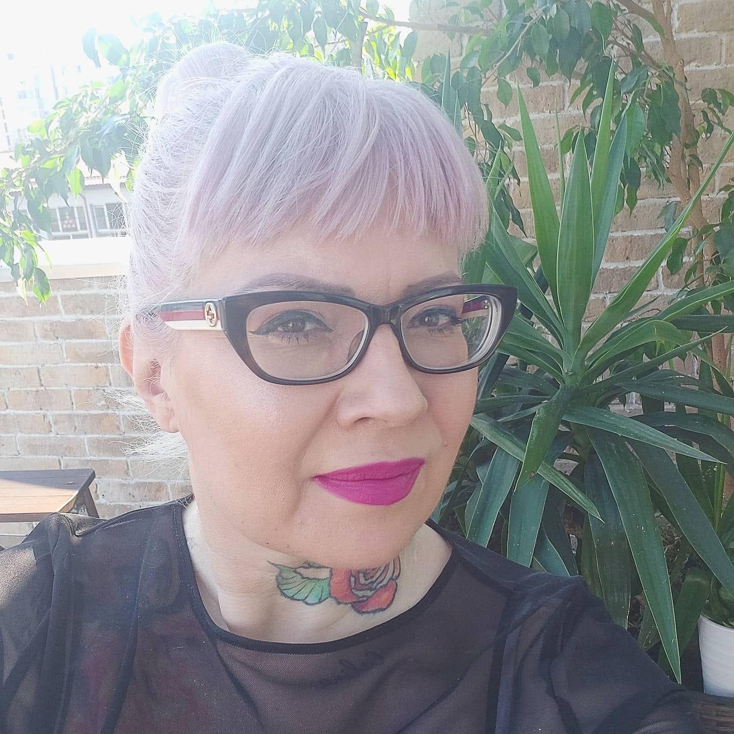 Catinca Roman îmbrăcată cu o bluză neagră, machiată cu un ruj roz