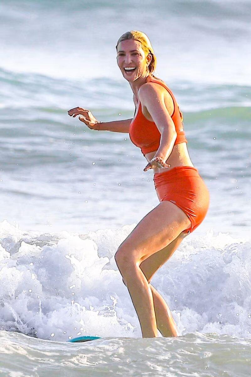 Ivanka Trump îmbrăcată într-un costum de baie portocaliu, facând surf