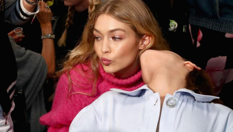 Bella Hadid, îmbrăcată cu o cămașă bleumarin, alături de sora ei, Gigi Hadid, îmbrăcată cu un pulover roz