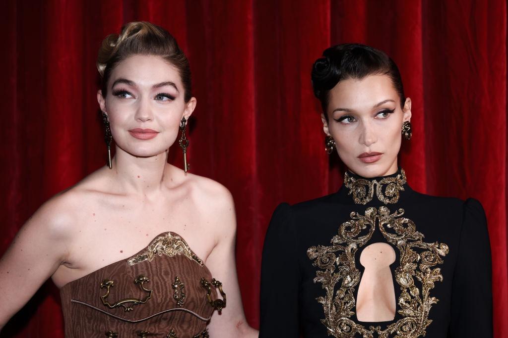 Bella Hadid, îmbrăcată într-o ținută neagră, alături de sora ei, Gigi Hadid, îmbrăcată cu o rochie maro fără mâneci