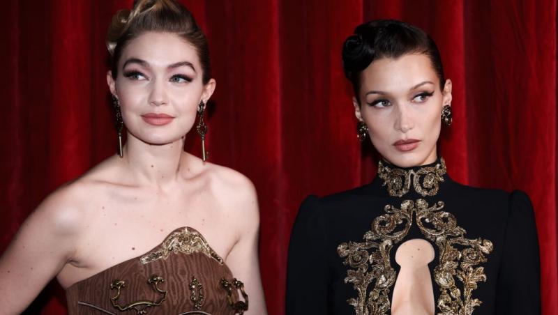 Bella Hadid, îmbrăcată într-o ținută neagră, alături de sora ei, Gigi Hadid, îmbrăcată cu o rochie maro fără mâneci