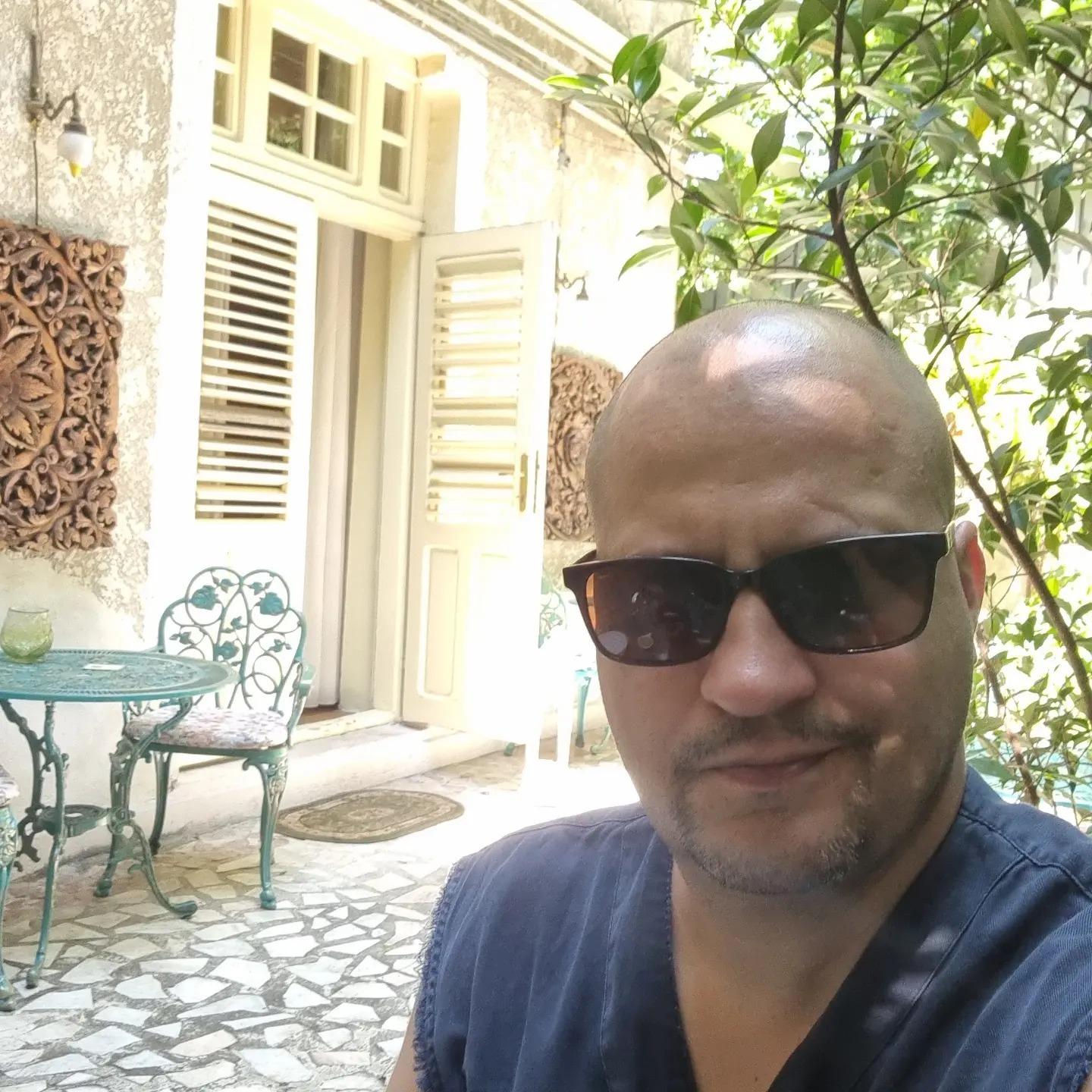 Șerban Huidu îmbrăcat cu un tricou din denim, purtând ochelari de soare