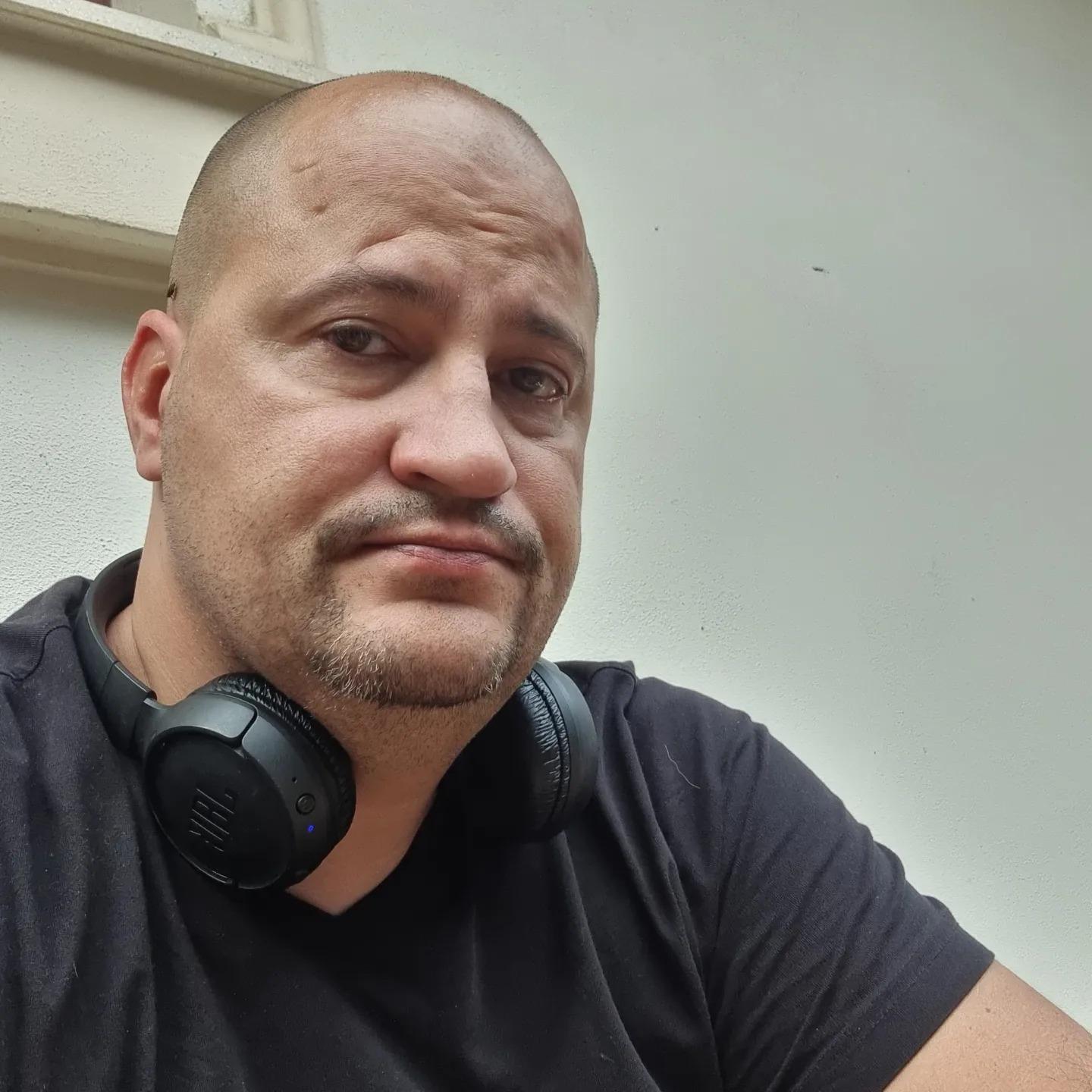 Șerban Huidu îmbrăcat cu un tricou negru și cu o pereche de căști la gât