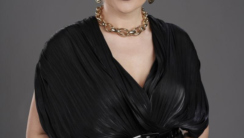 Mirela Vaida în studio, revine la Acces direct, pe fundal gri, îmbrăcată în bluză neagră cu fustă albă