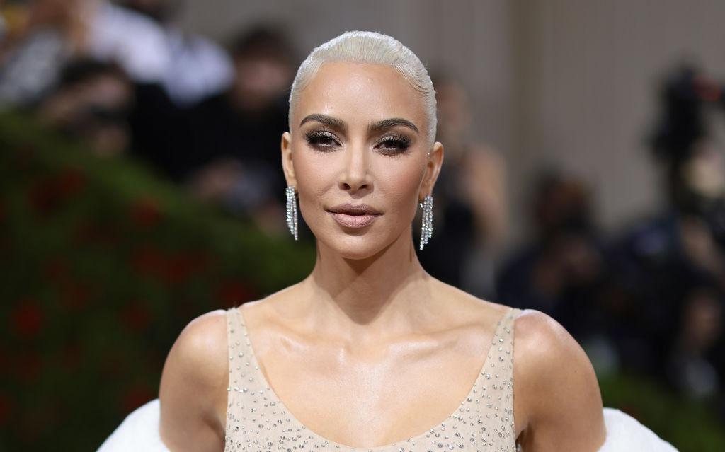 Kim Kardashian îmbrăcată cu o rochie bej împodobită cu pietre prețioase, accesorizată cu cercei strălucitori