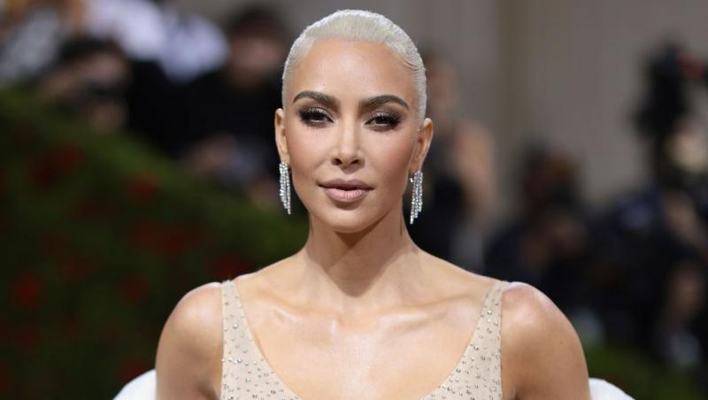 Kim Kardashian îmbrăcată cu o rochie bej împodobită cu pietre prețioase, accesorizată cu cercei strălucitori