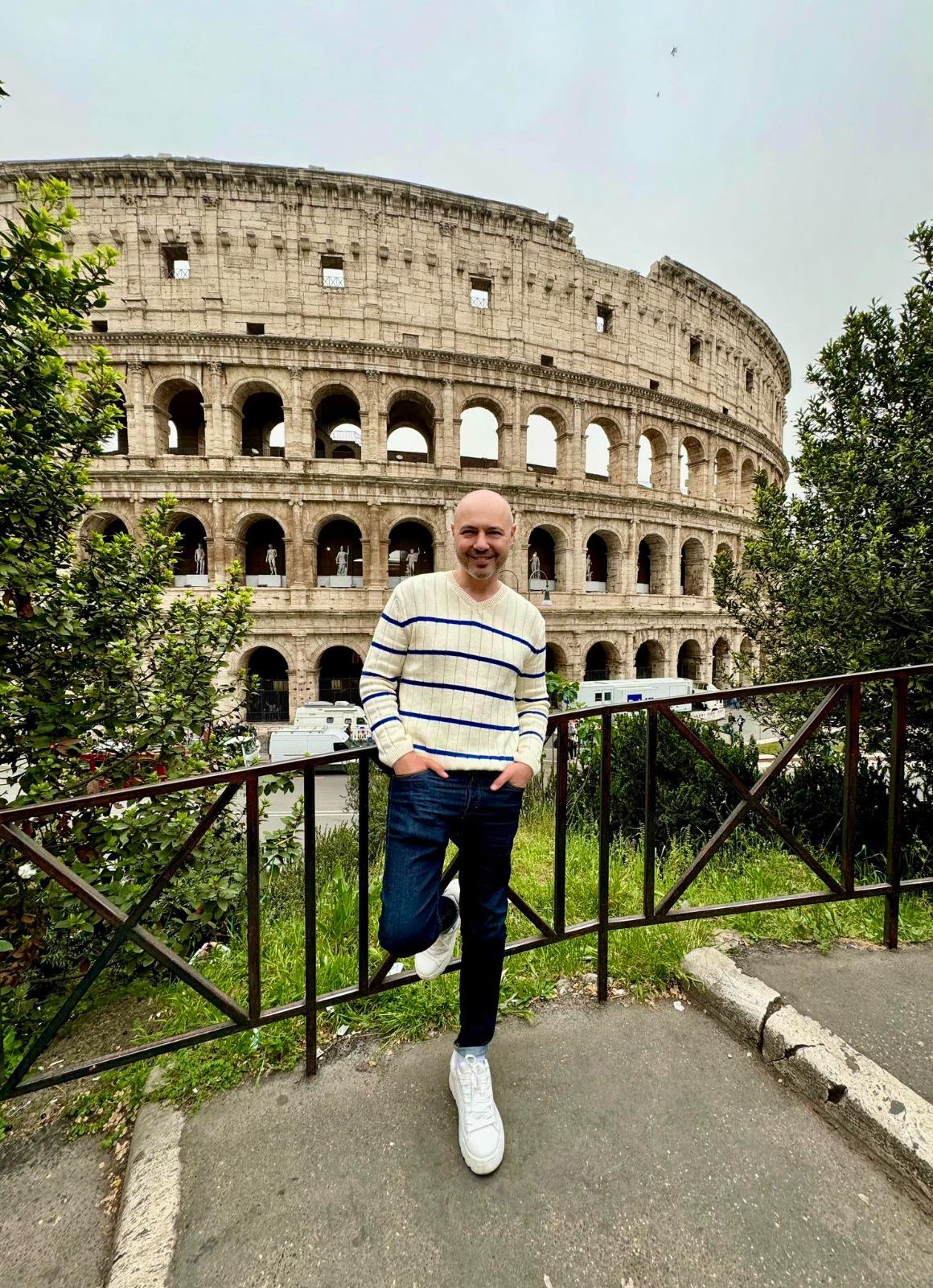 Mihai Mitoșeru îmbrăcat casual, pozând în fața Colosseumului